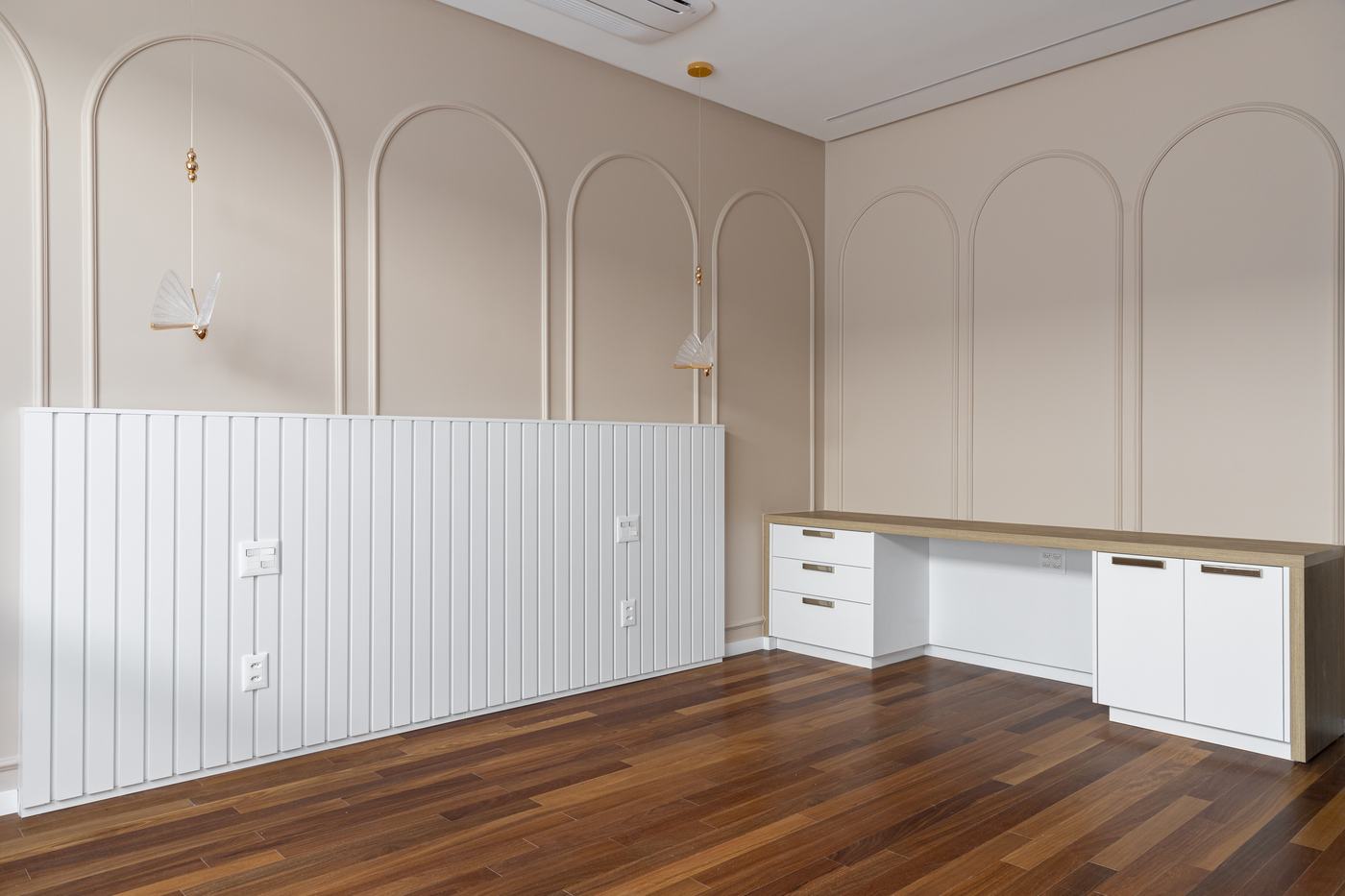 Quarto infantil com cabeceira em painel ripado branco, escrivaninha branca com tampo amadeirado e boiserie em arcos