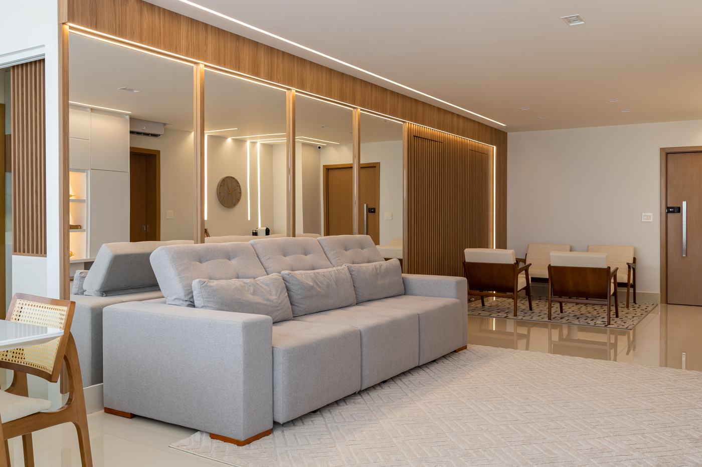 Sala com painel amadeirado com espelhos, frisos de LED e ripado